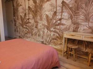 een slaapkamer met een bureau en een muur met een muurschildering bij Hôtel Du Patriarche in Agde