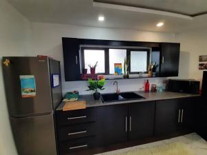 a kitchen with black cabinets and a stainless steel refrigerator at Serenity Cove - A Home Away From Home in Bel Ombre