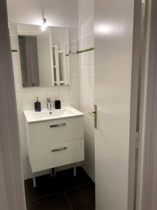 a white bathroom with a sink and a mirror at Les Capucins.Appartement élégant,Vue sur le jardin in Brest