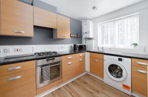 a kitchen with wooden cabinets and a washer and dryer at Charming 2BR Ground Floor Flat in Sholing, 11 Mins from City Centre - Recently Set Up with Love in Southampton