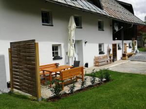 ein weißes Haus mit einem Holztisch und einer Bank in der Unterkunft Ferienhaus Krallinger in Abtenau