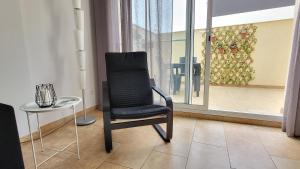 een zwarte stoel naast een tafel en een raam bij Somnis del Delta in Deltebre