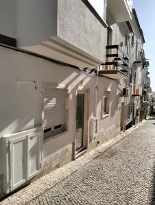 a white building with a window and a street at Casas da Cacilda II in Nazaré