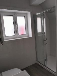 ein Bad mit einer Dusche und einem WC sowie zwei Fenster in der Unterkunft Casas da Cacilda II in Nazaré