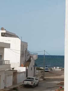 une voiture blanche garée dans une rue à côté d'un bâtiment dans l'établissement Residence de la plage, à Port El-Kantaoui