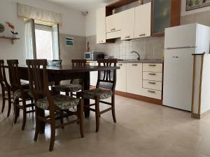 La cuisine est équipée d'une table, de chaises et d'un réfrigérateur. dans l'établissement Casa vacanze CoMì, à Santa Maria del Cedro