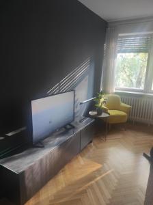 a living room with a flat screen tv and a yellow chair at Astralis Factory Apartments- Max in Zagreb