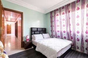 - une chambre avec un lit et un mur orné de fleurs roses dans l'établissement Homestay, Private room ,Séjours chez l'habitant Casa Voyageurs, à Casablanca