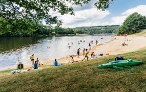 eine Gruppe von Menschen an einem Strand in der Nähe eines Wasserkörpers in der Unterkunft Chalet Park Jouillat 