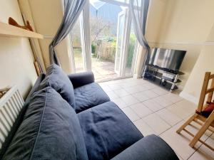ein Wohnzimmer mit einem blauen Sofa und einem TV in der Unterkunft Orford Village Room in London