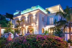 une grande maison blanche avec des fleurs devant elle dans l'établissement Hotel Villa Sirena - Thermae & SPA, à Ischia