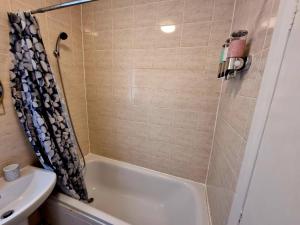 ein Badezimmer mit einer Badewanne und einem Waschbecken in der Unterkunft Orford Village Room in London