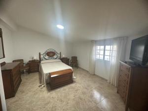 a bedroom with a bed and a dresser and a television at O Castro Sanxenxo in Sanxenxo