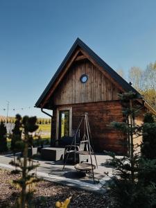 una cabaña de madera con un columpio delante de ella en Sosnowe Domki, en Warpuny