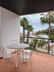 um pátio com uma mesa, cadeiras e palmeiras em Sunshine beach front complex, WiFi, modern em Casares