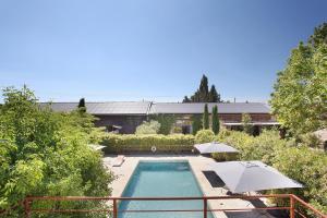 una piscina con 2 sombrillas y una casa en Haras Saint Estève, en Saint-Andiol