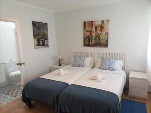 1 dormitorio con 1 cama blanca grande con almohadas azules en Precioso piso en playa America con jardin privado., en Nigrán