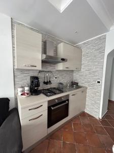 een keuken met witte kasten en een fornuis met oven bij Sun Garden Home in Somma Vesuviana