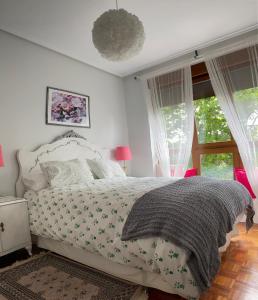 sypialnia z łóżkiem z białą narzutą i oknami w obiekcie Apartamento La Muralla parking gratis w mieście Burgos