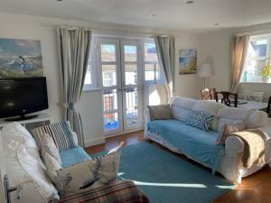 a living room with a blue couch and a tv at Beau retreat lovely apartment in Beaumaris in Beaumaris