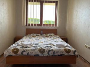 a bedroom with a bed with a comforter and two windows at EGGO APARTMENT - Oasis Beach Apartments Kamchia in Dolen Bliznak