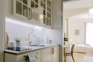 a kitchen with white cabinets and a sink and a bed at CYPRIAN apartment in Banská Štiavnica