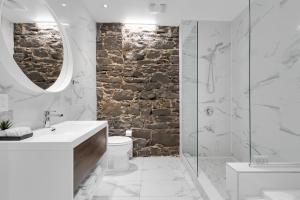 Baño blanco con pared de piedra en Bakan- Saint Francois Xavier, en Montreal
