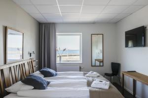 a bedroom with a bed with a view of the beach at Hotell Hamnen in Färjestaden