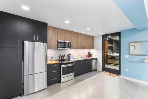 a kitchen with black cabinets and a stainless steel refrigerator at Airy and Open Corner Loft - 92 Walkscore in Redmond