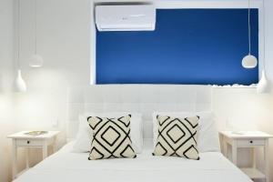 uma cama branca com duas almofadas e uma parede azul em Seagull Luxury Maisonette em Itea