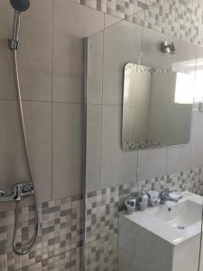 uma casa de banho com um chuveiro, um lavatório e um espelho. em Casa Da Praça em São Pedro do Corval