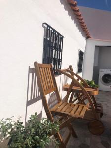 two wooden chairs sitting on the porch of a house at Casa Da Praça in São Pedro do Corval