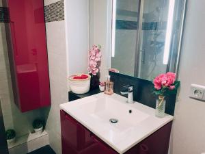 een badkamer met een witte wastafel en een vaas met roze bloemen bij La Clef du Bonheur - 9 Min de Disney Jardin privatif in Bailly-Romainvilliers