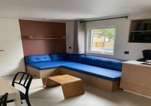a living room with a blue couch and a window at Charmant dans camping 5 étoiles-lac in Biscarrosse