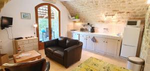 een woonkamer met een leren stoel en een keuken bij Mas Le Corbery in Largentière