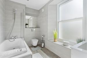 a bathroom with a tub and a toilet and a sink at Rutland Heights - Luxury Apartment in Torquay