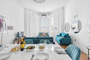 a white living room with a table and blue chairs at Rutland Heights - Luxury Apartment in Torquay