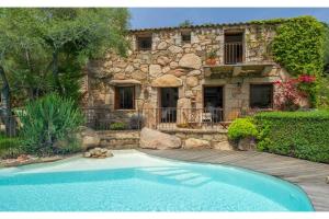 a stone house with a swimming pool in front of it at Les Lauriers Roses Palombaggia Porto-Vecchio in Porto-Vecchio