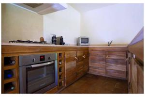a kitchen with wooden cabinets and a stove top oven at Les Lauriers Roses Palombaggia Porto-Vecchio in Porto-Vecchio