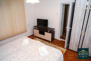 een kleine kamer met een bed en een televisie bij Apartmani Rajkovic in Soko Banja