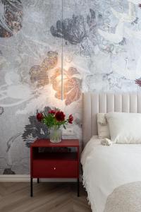 een slaapkamer met een bed en een rode tafel met bloemen erop bij Fresh unit, high quality design. in Tallinn