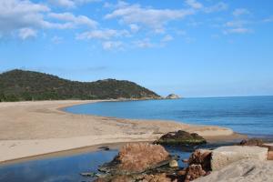 a beach with rocks and the ocean on a sunny day at Altura in Zonza +3 photos