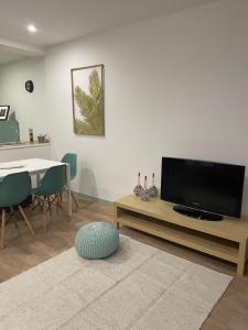 uma sala de estar com uma televisão de ecrã plano e uma mesa em Casa dos Arcos em Vila do Conde