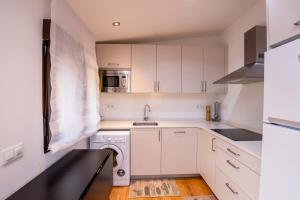 uma cozinha branca com um lavatório e uma máquina de lavar roupa em Cerezal 3, Loft en plena naturaleza em Llanes