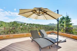 un patio avec deux chaises et un parasol sur une terrasse dans l'établissement Sunlit Hills Art and Views, 3 Bedrooms, Sleeps 6, Hot Tub, Volleyball, WiFi, à Santa Fe