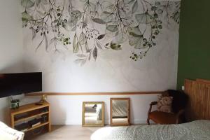 a bedroom with a painting of leaves on the wall at Le Raffiné in Millau