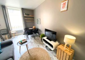 uma sala de estar com um sofá, uma televisão e uma mesa em La Comédie - Poitiers Centre - La Conciergerie. em Poitiers