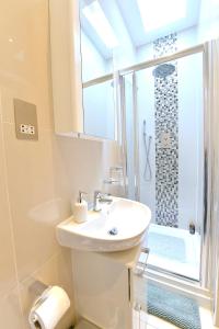 uma casa de banho branca com um lavatório e um chuveiro em Hendon Escape Luxury Apartment with En-suite Bath em Hendon
