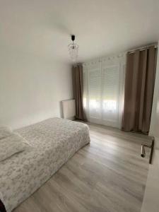 biała sypialnia z łóżkiem i drewnianą podłogą w obiekcie Appartement Gien w mieście Gien