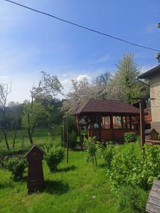 a wooden cabin in a grassy yard with a house at Гостьовий двір in Yaremche